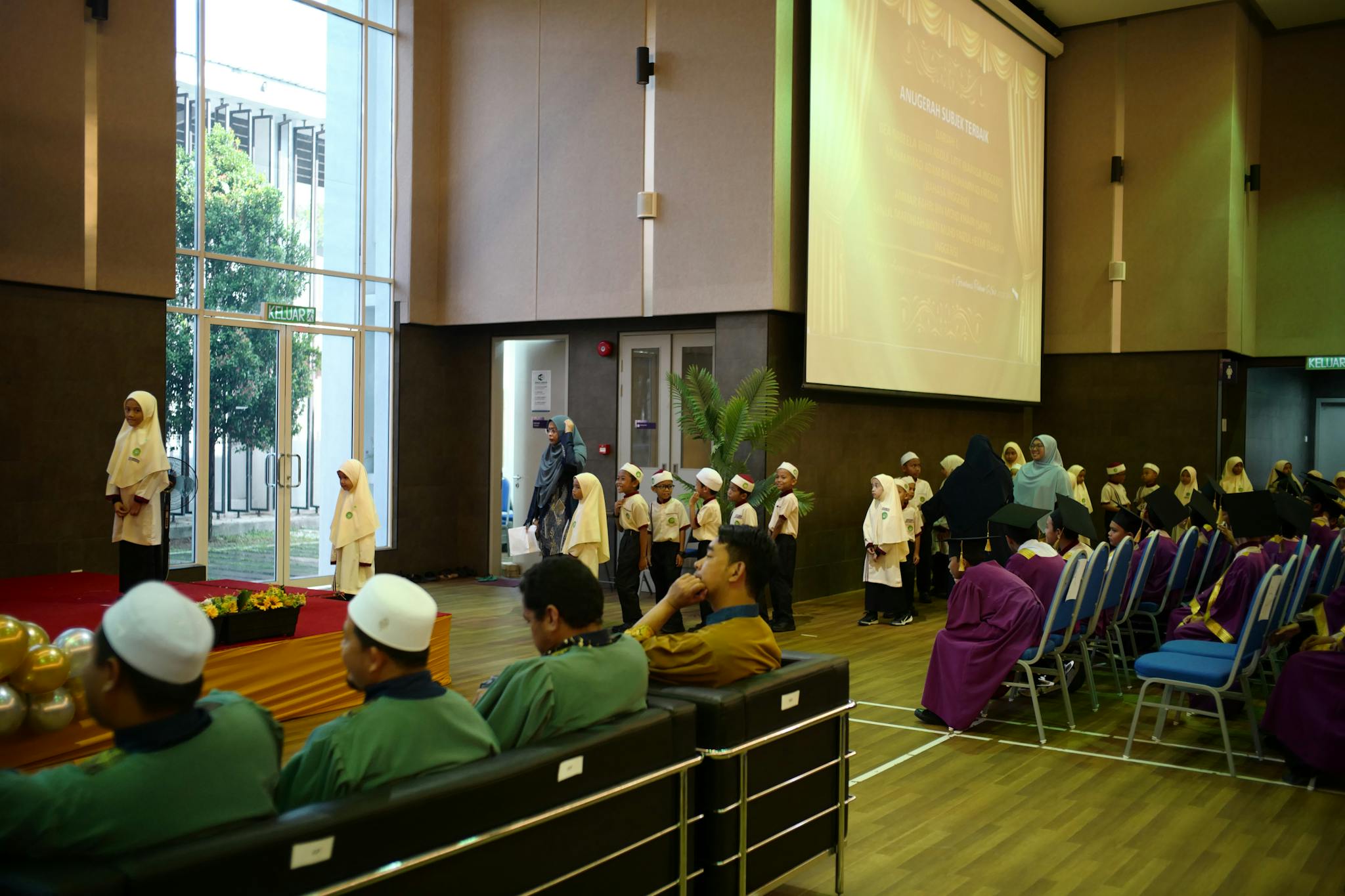 Young students in traditional attire at a school graduation ceremony in Shah Alam, Malaysia.